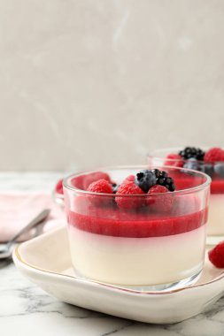 Meyve soslu lezzetli panna cotta ve beyaz mermer masada servis edilen taze böğürtlen.