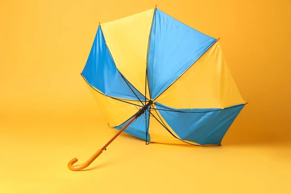 黄色背景的木制把手折断了的明亮的伞 — 图库照片