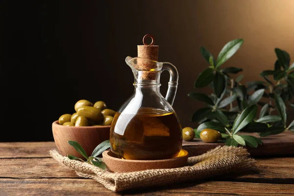 Glazen Kruik Met Olie Rijpe Olijven Groene Bladeren Houten Tafel — Stockfoto