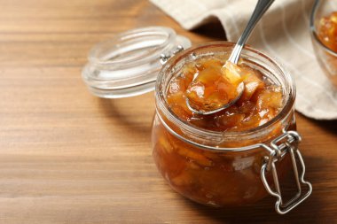 Ahşap masada cam kavanozda lezzetli elma reçeli ve kaşık, yakın plan. Metin için boşluk