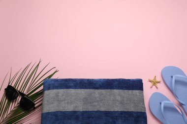 Plaj havlusu, parmak arası terlik ve pembe arka planda güneş gözlüğü. Metin için boşluk