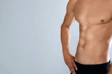 Gri arka planda zayıf vücutlu, üstsüz bir adam, yakın plan. Metin için boşluk