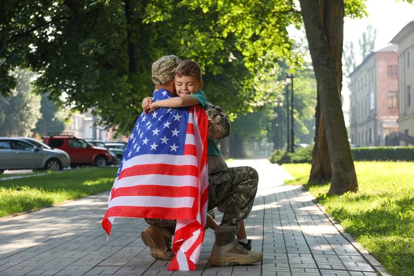 アメリカの旗を持った兵士と彼の息子は屋外で抱き合って — ストック写真