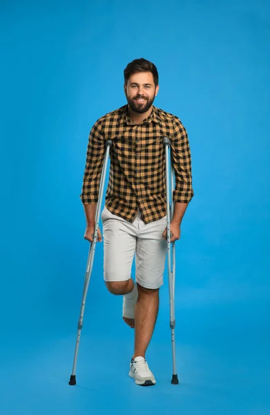 足を負傷した若いです脚を使用して軸性松葉杖上のライトブルーの背景 — ストック写真