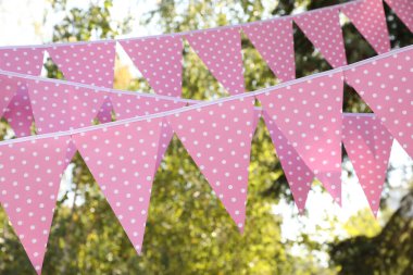Pink bunting flags in park. Party decor clipart