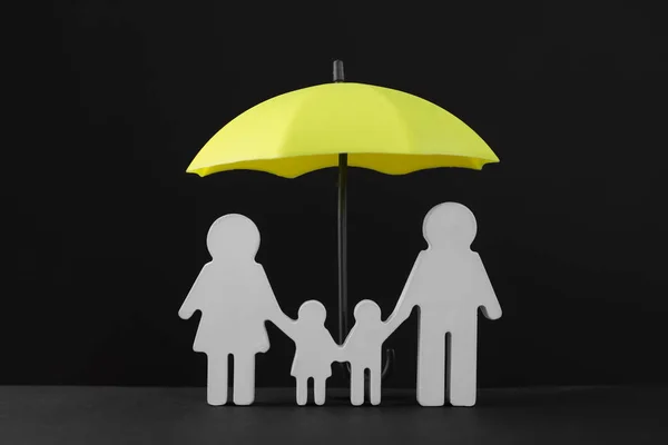 黒を背景にした小さな傘と家族の姿 — ストック写真