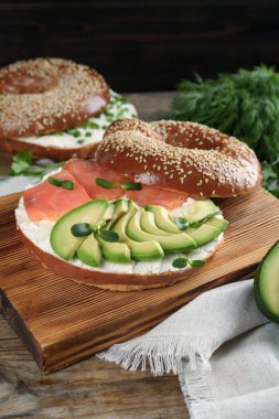 Krem peynirli lezzetli simit, somon, avokado ve ahşap masada mikro yeşillikler.