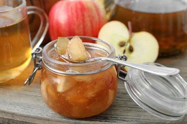 Delicious apple jam in jar on wooden table, closeup