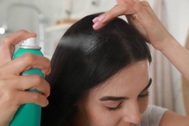 Kapalı alanda saçına kuru şampuan süren bir kadın.