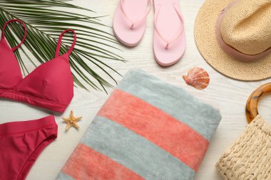 Havlu ve beyaz ahşap arka planda farklı plaj aksesuarları.