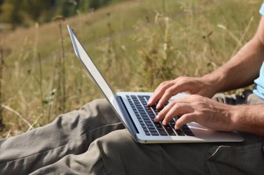 Güneşli bir günde dışarıda dizüstü bilgisayarla çalışan adam, yakın plan.