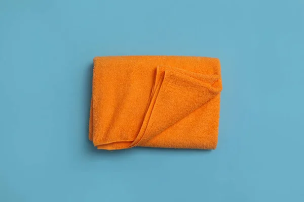 薄い青の背景に折られたオレンジのビーチタオル トップビュー — ストック写真