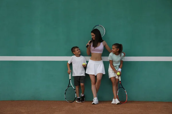 Genç Bir Kadın Çocukları Tenis Kortunda Yeşil Duvarın Yanında — Stok fotoğraf