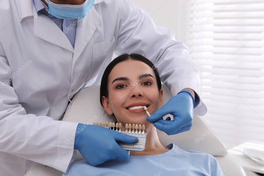 Dentist checking young woman's teeth color in clinic