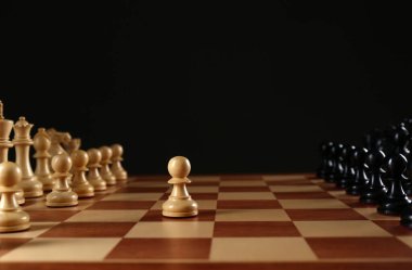 Siyah arka plana karşı tahta tahtadaki satranç taşları