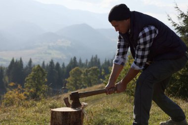 Tepede yakacak odun kesen baltalı yakışıklı adam.