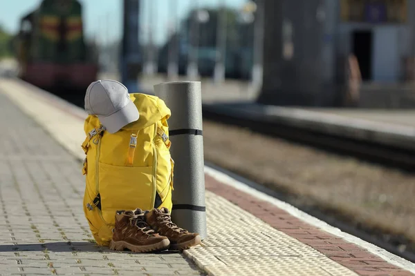 黄色のバックパック ハイキングブーツ 屋外鉄道プラットフォーム上のキャンプマット 観光コンセプト — ストック写真