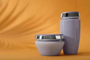 Turuncu arka planda saç bakımı kozmetik ürünleri, metin için alan