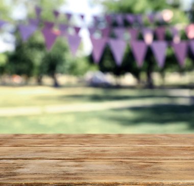 Parktaki boş ahşap masa kiraz bayraklarıyla süslenmiş, tasarım için yer var. Açık hava partisi.