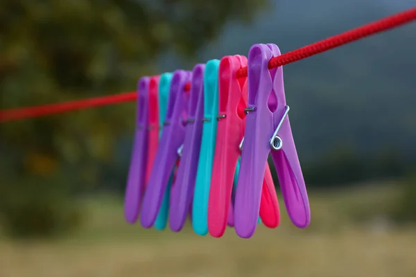 Colorful clothespins hanging on washing line outdoors, closeup