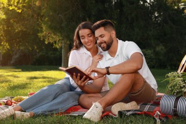 Parkta ekose kitap okuyan mutlu genç çift. Yaz pikniği