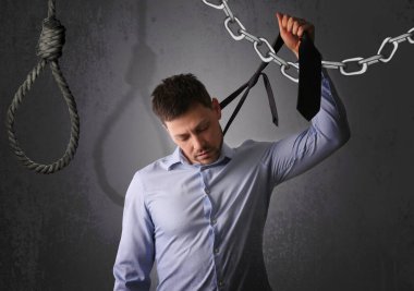 Depresyondaki işadamı, gri arka planda ilmek gibi kravat tutuyor.