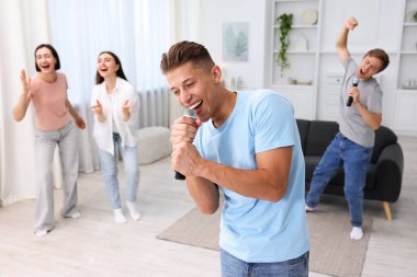Genç adam evde arkadaşlarıyla karaoke yapıyor, seçici odaklı.