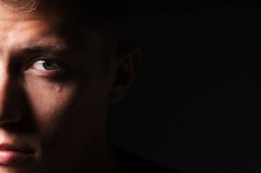 Sad man crying on black background, closeup