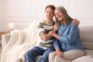 Mutlu oğul ve annesi evdeki kanepede birlikte vakit geçiriyorlar. Metin için boşluk