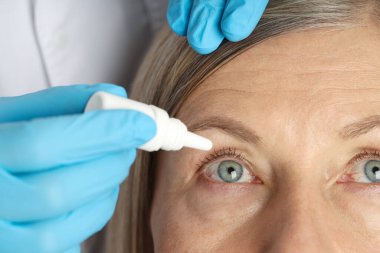 Doktor iç mekânda kadınların gözüne damla damlatıyor.