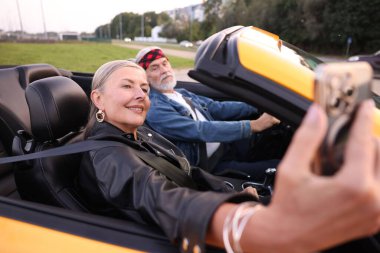 Üst düzey kadın özçekim yaparken erkek açık havada Cabriolet kullanıyor, seçici odaklanma.