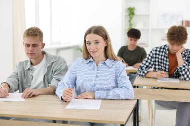 Ahşap masada sınava giren öğrenciler