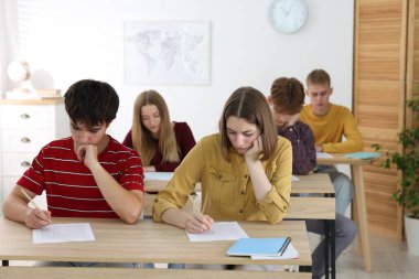 Ahşap masada sınava giren öğrenciler