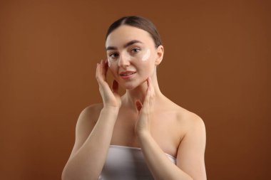 Kahverengi arka planda krem sürmüş güzel bir kadın.