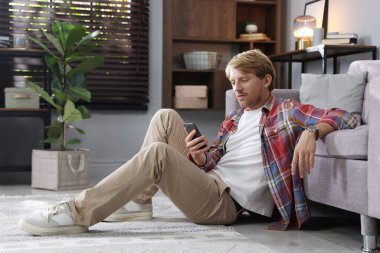 Adam evde yerde akıllı telefon kullanıyor.