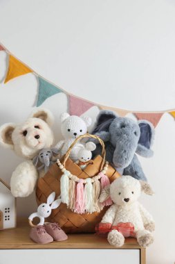 Beyaz duvarın yanındaki çekmecelerde farklı oyuncaklar.