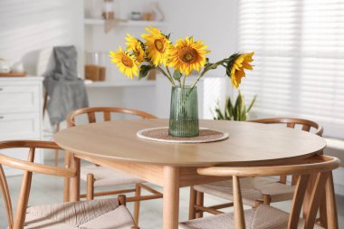 Beautiful sunflowers in vase on dining table at home