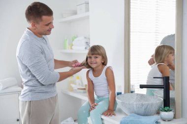 Babası banyoda kızının saçını tarıyor.