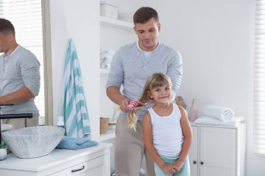 Babası banyoda kızının saçını tarıyor.