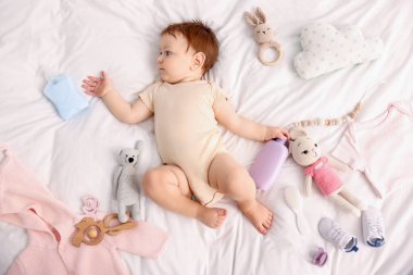 Güzel bebek ve yatağın üstünde farklı aksesuarlar.