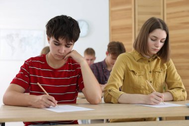 Ahşap masada sınava giren öğrenciler