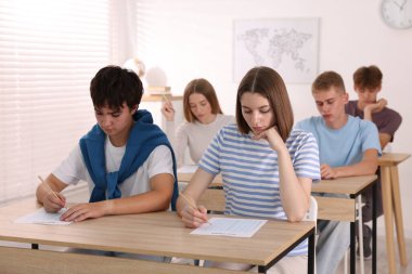 Ahşap masada sınava giren öğrenciler