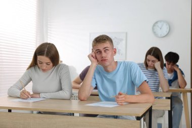 Ahşap masada sınava giren öğrenciler