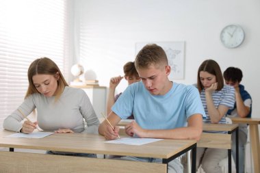 Ahşap masada sınava giren öğrenciler