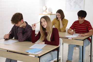 Ahşap masada sınava giren öğrenciler