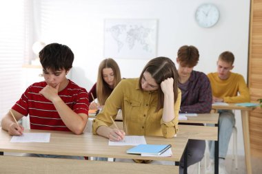 Ahşap masada sınava giren öğrenciler