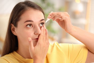 Evde göz damlası süren genç bir kadın.