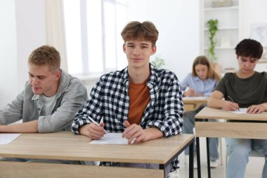 Ahşap masada sınava giren öğrenciler