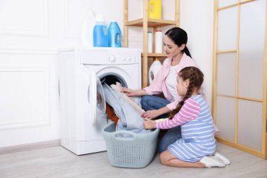 Küçük yardımcı. Anne ve kızı evde çamaşır yıkıyorlar.