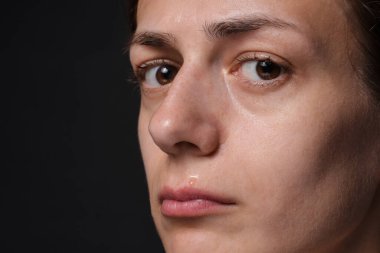 Üzgün kadın siyah arka planda ağlıyor, yakın plan. Metin için boşluk